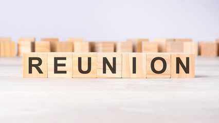 text REUNION on wooden cubes on bright grey background. square wood blocks. top view, flat