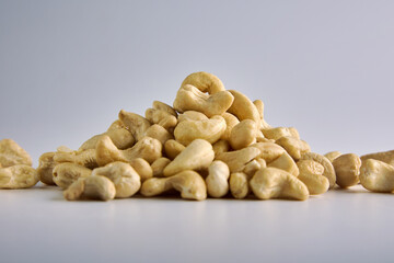 Fototapeta na wymiar Raw cashew nuts on a gray background are laid out with a slide to get an appetizing photo. Advertising of healthy snack foods for vegetarians