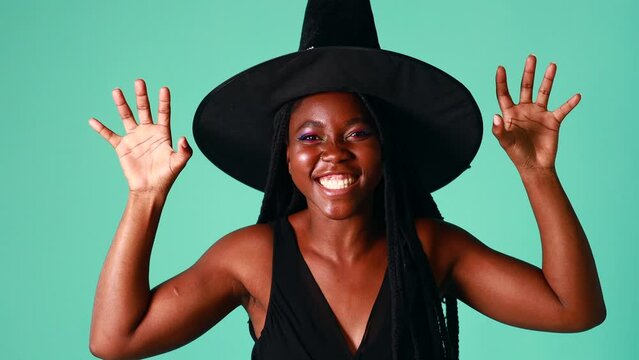 Young beautiful woman wearing witch halloween costume smiling cheerful in blue background in studio