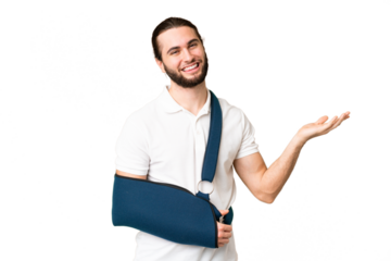 Young handsome man with broken arm and wearing a sling over isolated chroma key background extending hands to the side for inviting to come