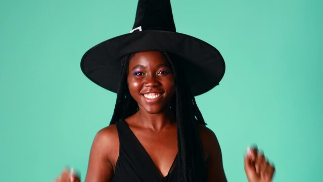 Young beautiful woman wearing witch halloween costume smiling cheerful in blue background in studio