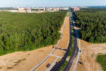Aerial view of the road under construction leading to the city through the forest