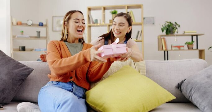 Home, lesbians and couple with a surprise, gift and bonding in living room, happiness and relax. Partners, women and queer people in their lounge, present and celebrate relationship, marriage and wow