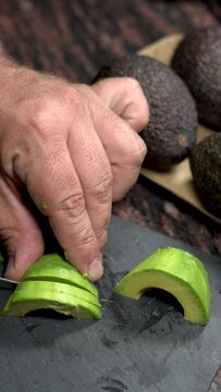 One person slicing fresh avocado on a table