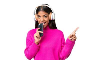 Young African American woman over isolated background listening music with a mobile and singing