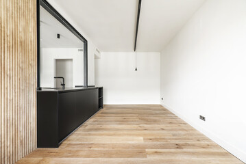 Living room of a recently renovated empty house with a black cabinet with a hatch to the kitchen