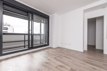 An empty living room of an apartment with wooden flooring with access to a terrace through