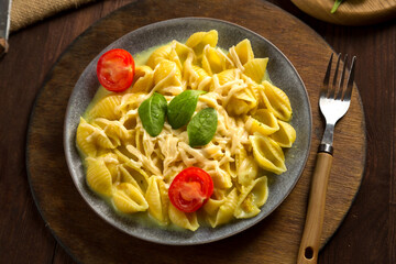 Pasta in cream sauce with cheese garnished with spinach with a fork on a wooden stand.