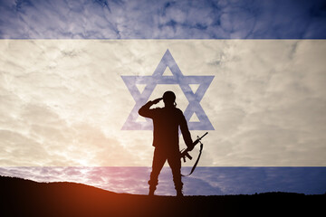 Silhouette of soldier saluting against the sunrise in the desert and Israel flag. Concept - armed...