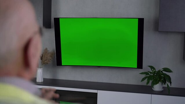 Elderly pensioner watches football on television and reacts at game with angry expression. Old man spends pastime watching TV at home