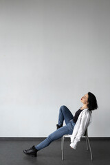 A woman in a white shirt sits on a chair