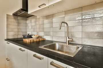 Fototapeta na wymiar a kitchen with black counter tops and white tiles on the wall behind it is a stainless fauced sink
