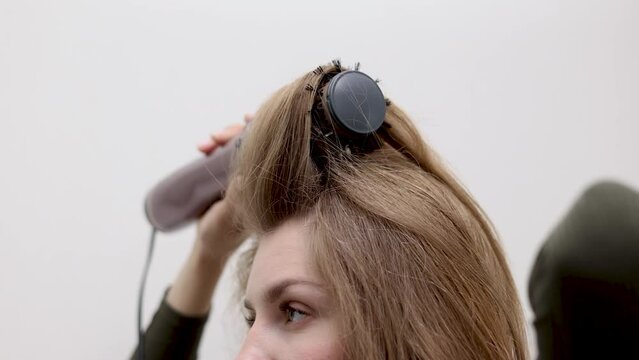 beautiful young woman using rotative brush hair styler for hair.female girl with long dark blonde hair.smiling woman in mirror.4k