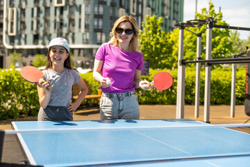 Happy Mother and Daughter Learning to Play Ping Pong Sport Cheerful family playing leisure sports enjoying table tennis