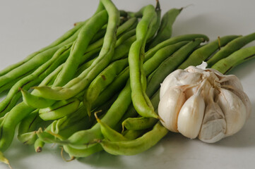 Some green beans and a garlic bulb isolated on a white background