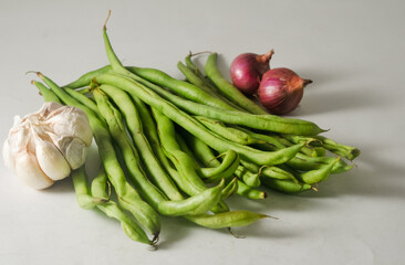 Some green beans and a garlic bulb, two red onions isolated on a white background
