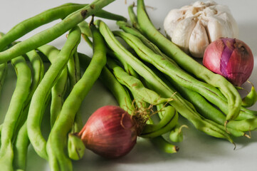 Some green beans and a garlic bulb, two red onions isolated on a white background