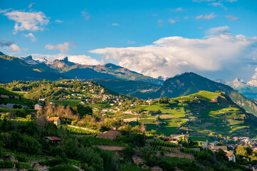 Fototapeta na wymiar Idyllic Highlands near Sion, Switzerland at sunny summer day. Tranquility of the rolling hills adorned with charming farmhouses and lush vineyards, creating a serene and idyllic scene