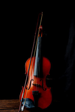 Violin, details of a beautiful violin on rustic wood, low key style photo, black background, selective focus.