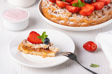 Sweet cake with strawberries on plate on white wooden background
