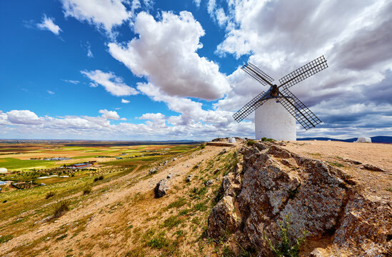 Wind mill at knoll in Consuegra, Toledo region, Castilla La Mancha, Spain. Route of Don Quixote with windmills. Summer landscape with blue sky and clouds