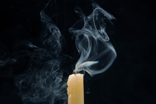 Smoke from an extinguished candle on a dark background. The concept of spirituality and the end of life.