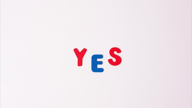 The word yes on a light gray background stop motion video. Blue and red letters form the word yes.