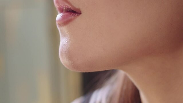 Young woman lining her lips with a dark nude pencil