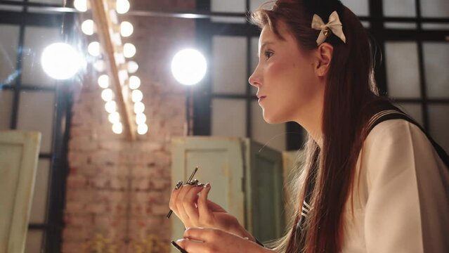 Young beautiful woman doing eye makeup in dressing room
