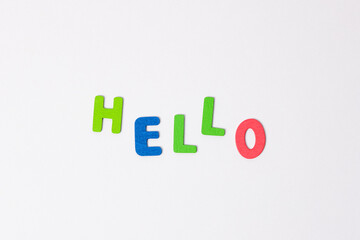 The word hello made of colored wooden letters on a light gray background. Blue and red letters form the greeting word hello.