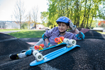 portrait of a child in a purple helmet with multi-colored plastic city cruisers, skateboards.