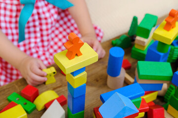 little four year old boy has fun playing at home with wooden blocks building tower under isolation, development of fine motor skills, simulation is the leading activity of children