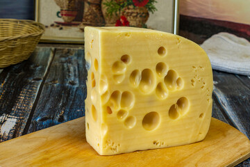 Cheese with holes on the board close-up.