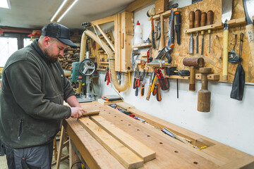 Carpenter removing wood shavings from planks using brush in a woodworking studio. High quality photo