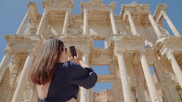 Female tourist visiting and taking pictures of Celsus Library in ancient city Ephesus, Anatolia in Selcuk, Turkey. Slow motion
