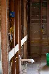 Kitchen wall undergoing demolition and remodeling including rewiring by an electrician to meet building codes after the removal of plaster to expose framing