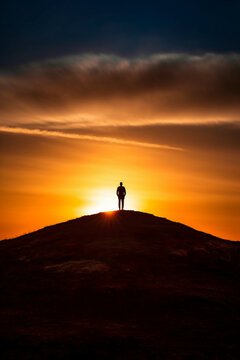 A dramatic silhouette of a person standing on a hill. AI generative