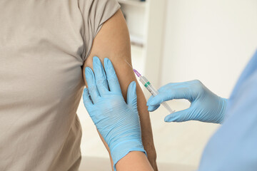 Doctor giving hepatitis vaccine to patient in clinic, closeup