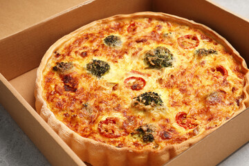 Delicious homemade vegetable quiche in carton box, closeup