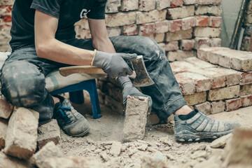 A young guy is cleaning bricks with an axe.