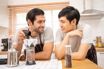 Fototapeta premium Cheerful Boyfriends gay LGBTQ lovely couple making a drip coffee brew in the kitchen together for breakfast.