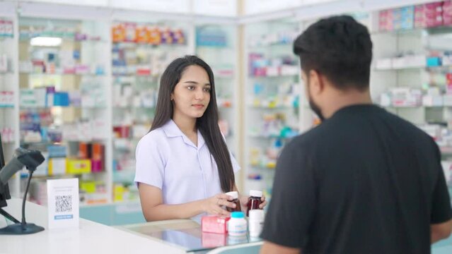 4K Attractive Indian woman pharmacist medication recommendation about medicine, drugs and supplements to man patient customer in modern drugstore. Medical pharmacy and healthcare providers concept.