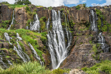A large waterfall with numerous cascades poring down a mountain side at Pangour Falls in Vietnam