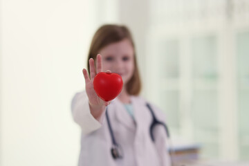 Cute little girl dressed as doctor holds red heart in hand