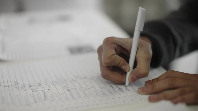 A man's hand signs with a pen in a magazine.