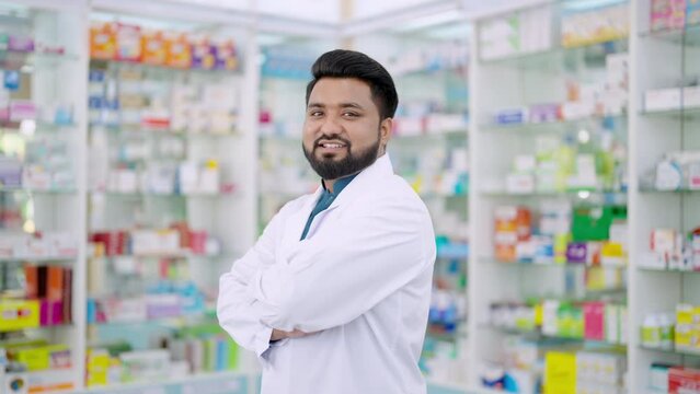 4K Portrait of Handsome Indian man professional pharmacist ready for medication advice about medicine, drugs and supplements in modern drugstore. Medical pharmacy and healthcare providers concept.