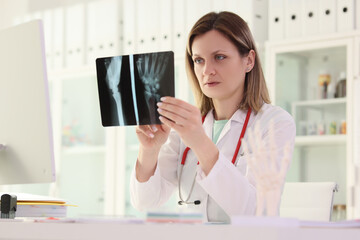 Doctor studies X-ray picture of patient arm sitting at table