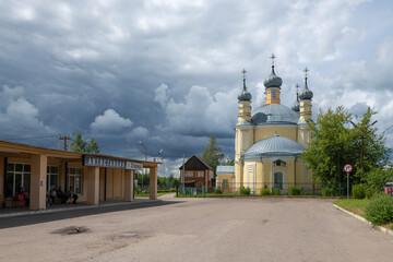 Fototapeta na wymiar The building of the city bus station and the Church of Elijah the Prophet on a cloudy July day, Staritsa