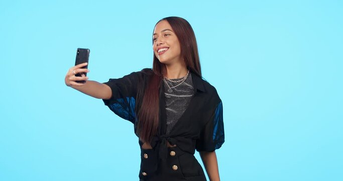 Selfie, smile and fashion of woman in studio isolated on a blue background mockup. Photography, trendy and stylish female person or influencer with profile picture, social media and happy memory.