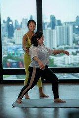 Obraz premium Fitness instructor trains fat woman stretching Yoga meditates against modern skyscrapers room on roof top of Condominium.
